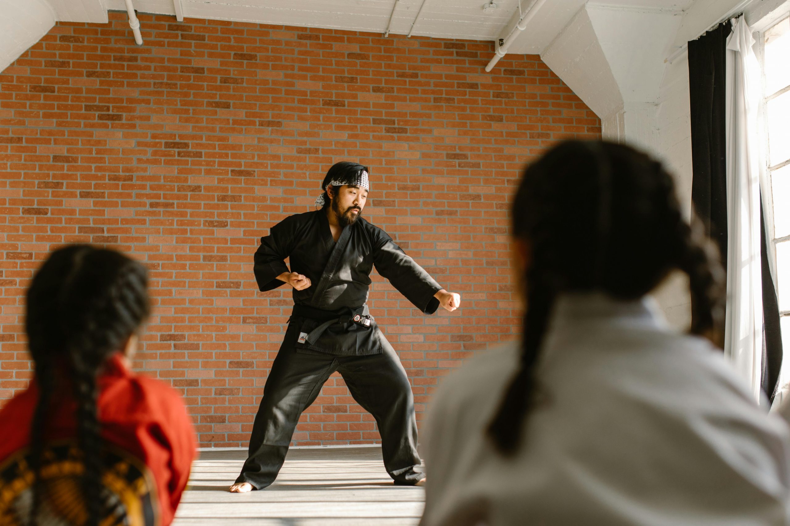 Martial arts instructor demonstrating moves to young students in a training dojo.